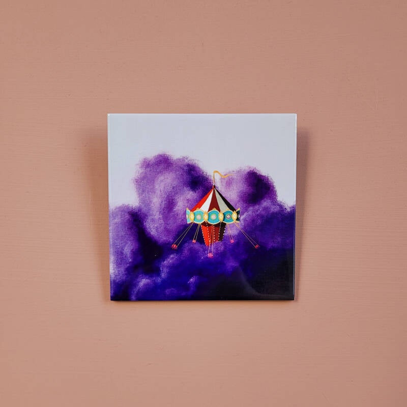 Een illustratie van een zweefmolen op een keramisch tegeltje van 10 x 10 cm.