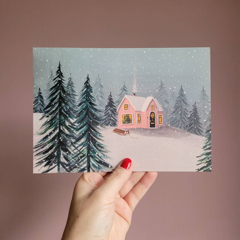 Een illustratie van een gezellig winterhuisje in de sneeuw op een A5 print.