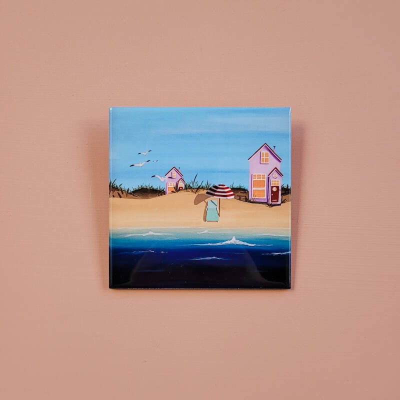 Een illustratie van een strandhuisje op een decoratieve keramische tegel van 10 x 10 cm.