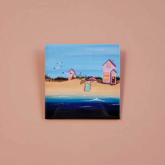 Een illustratie van een strandhuisje op een decoratieve keramische tegel van 10 x 10 cm.