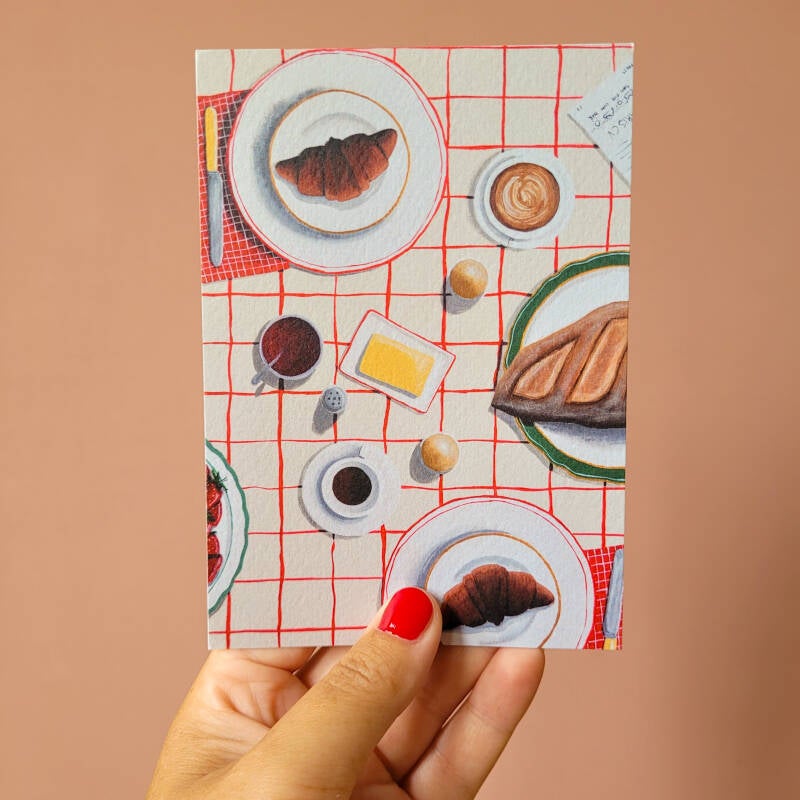 Een illustratie van een gezellige ontbijttafel op een A6 ansichtkaart.