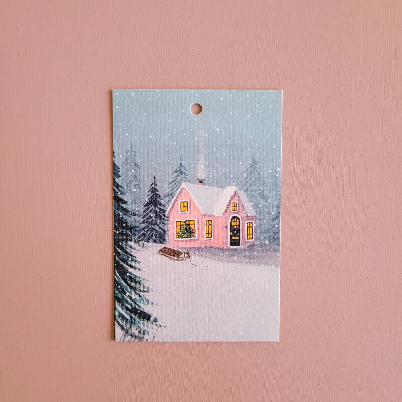 Een illustratie van een winterhuisje op een cadeaukaartje.