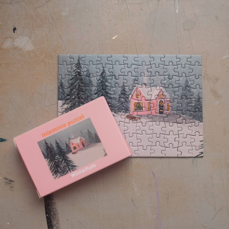 Een illustratie van een gezellig winterhuisje op een mini puzzel van 99 stukjes.