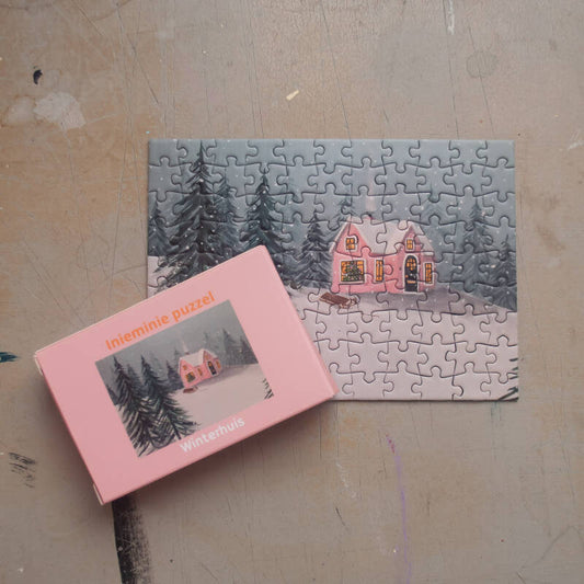 Een illustratie van een gezellig winterhuisje op een mini puzzel van 99 stukjes.