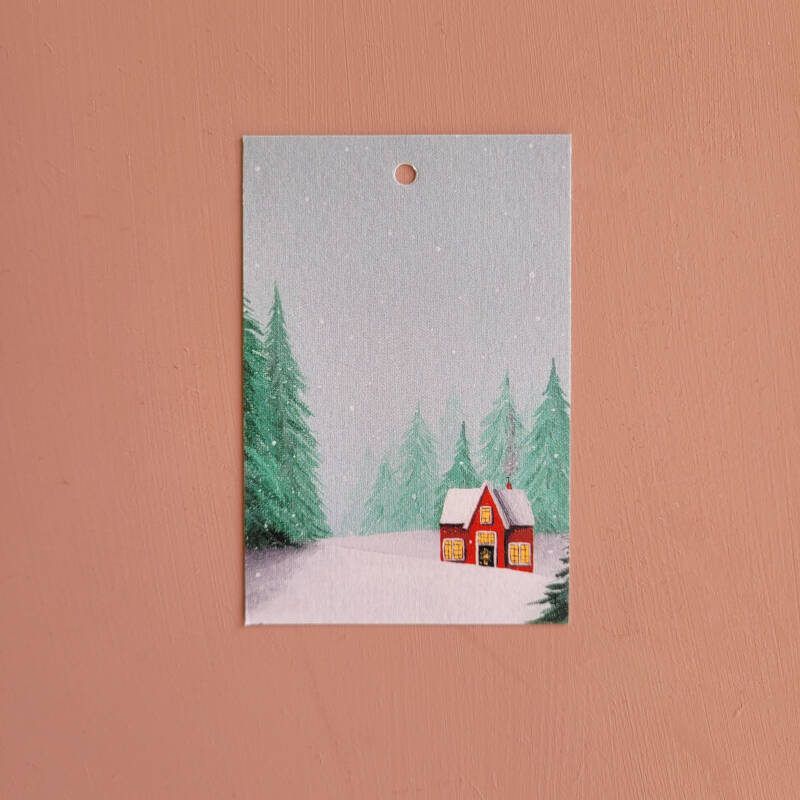 Een illustratie van een rood winterhuisje op een cadeaukaartje.