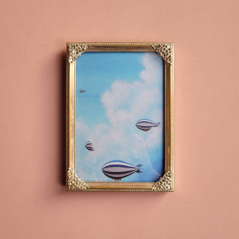 Een illustratie van zeppelins op een A5 print in een zilveren vintage lijstje met versierde hoekjes.