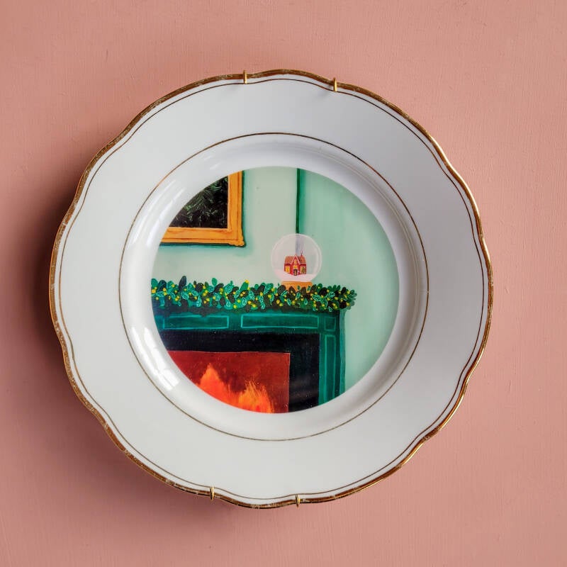 Een illustratie van een sneeuwbol op een wit vintage wandbord met een gouden art deco rand.