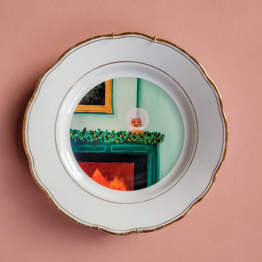 Een illustratie van een sneeuwbol op een wit vintage wandbord met een gouden art deco rand.