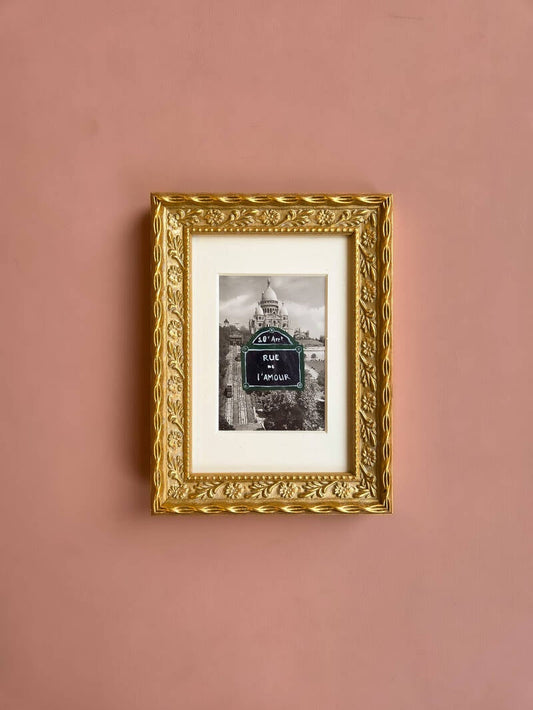 Een schilderij van een Parijs straatbordje met de tekst Rue de l'Amour op een vintage foto van Parijs.